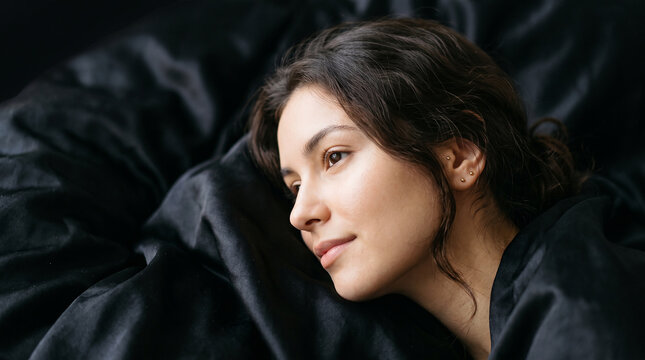 Peaceful gorgeous woman resting quietly under dark bed sheets perfectly reflecting relaxing comfortable mornings and cozy rest concepts