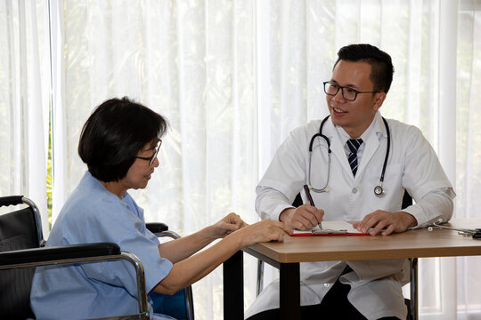 Doctor consulting adult woman in wheelchair at clinic while writing medical notes, showing healthcare, patient care, accessibility, treatment, communication and professional support