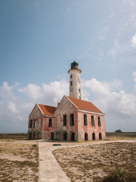 abandoned lighthouse stationary in deserted coastal area with arches and pathway leading up concrete brick metal structure, desolate and nostalgic mood, ground-level perspective looking up.
