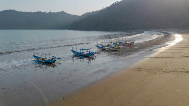 Drone shot of traditional Indonesian fishermen preparing wooden boats on Pujiharjo beach East Java