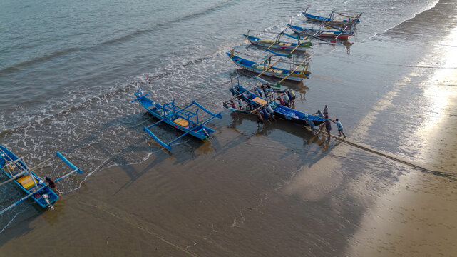 Drone shot of traditional Indonesian fishermen preparing wooden boats on Pujiharjo beach East Java