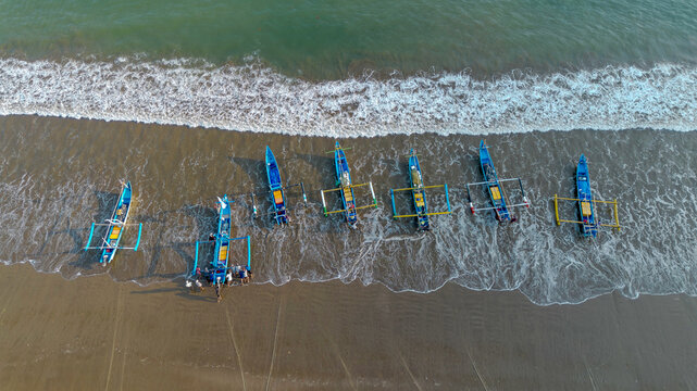 Drone shot of traditional Indonesian fishermen preparing wooden boats on Pujiharjo beach East Java