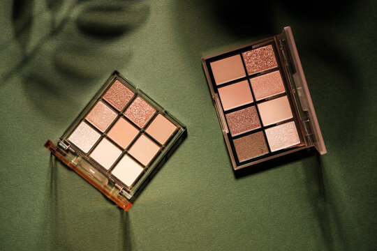 Eye shadow palettes with neutral shades on a green textured background
