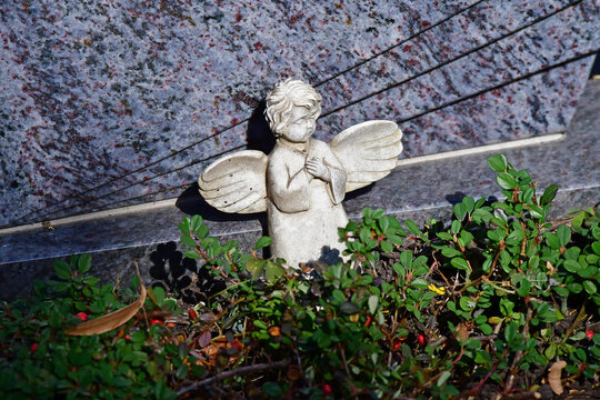 sweet angel figure on a grave in autumn with fallen leaves