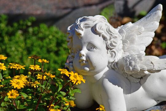 sweet angel figure on a grave in autumn with fallen leaves