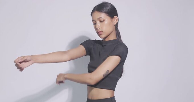 Fit Asian woman stretching her arms and shoulders before a workout. Fitness and healthy lifestyle concept.