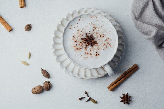 Chai latte with milk foam, cinnamon and star anise on a white background