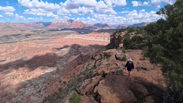 View a mature woman hiking along the scenic Gander Trail on Gooseberry Mesa, surrounded by awe-inspiring Utah scenery.