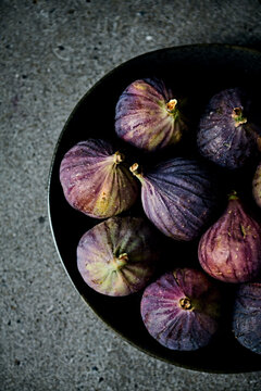 Fresh organic purple figs on a black ceramic plate