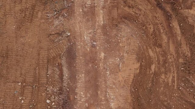 A view from above of a dusty plot of land with tire tracks and the texture of excavated soil at a construction site.