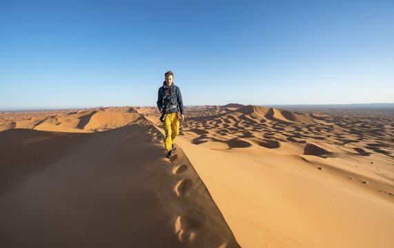Young man running on sand dune, Erg Chebbi, Merzouga, Sahara, Morocco