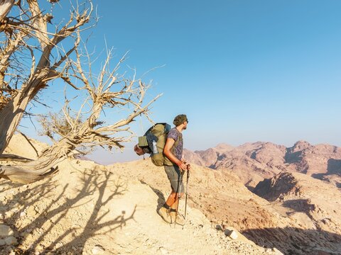 Jordan Trail hiker trekking rocky desert mountains near Petra with backpack and trekking poles adventure travel wilderness landscape. Jordan Trail is a 650 km long hiking trail in Jordan