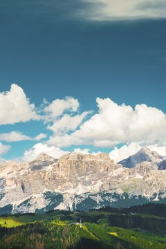 Panorama Dolomites mountain range Italy jagged peaks moving clouds blue sky alpine landscape summer nature rocky limestone ridge scenic vista horizontal panorama outdoor environment banner background