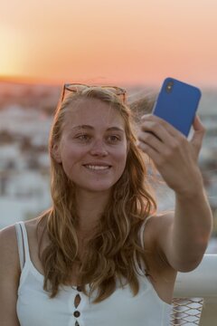 Young woman with white top photographs herself with a smartphone, selfie, sunset, Plaza de la Encarnacion, Seville, Andalusia, Spain