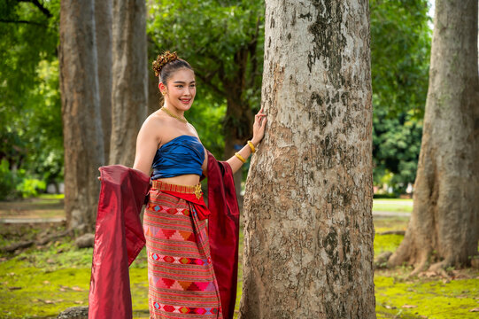 Northern Thai Lanna woman wearing hand-weaving intricate folk patterns onto a cotton sinh skirt and sabai shawl traditional local attire standing in tropical greenery natural green environment