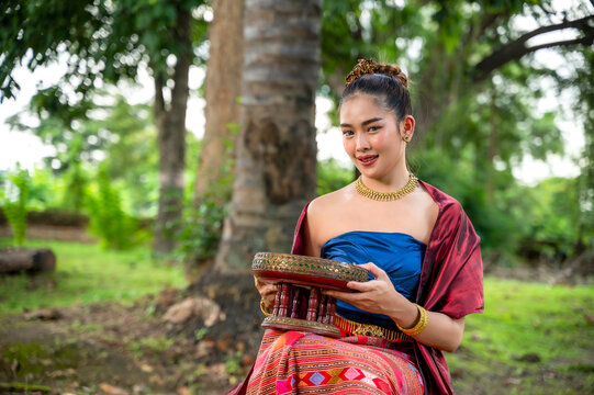 Northern Thai Lanna woman wearing hand-weaving intricate folk patterns onto a cotton sinh skirt and sabai shawl traditional local attire standing in tropical greenery natural green environment
