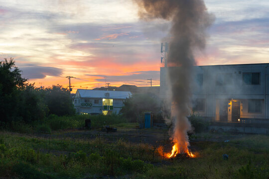 Smoke cloud rises over small fire in residential neighborhood at sunrise