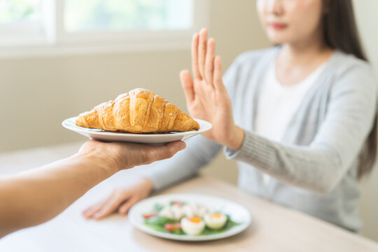Ketogenic, Low carb, Intermittent Fasting diet woman push out, deny hand push out, deny butter croissant bread on plate, choose green vegetable salad, eat food for good healthy, getting weight loss.