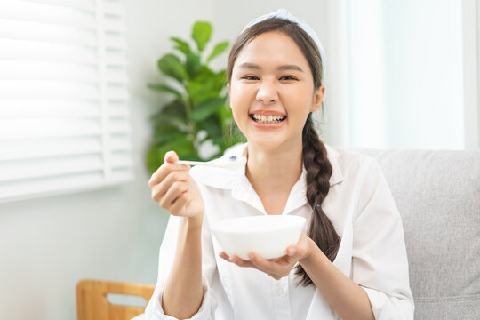 Healthy lifestyle, wellness food asian young woman hand use spoon eat tasty fresh organic yogurt, dairy product in bowl breakfast meal at home. Snack tasty on diet nutrition delicious natural yoghurt