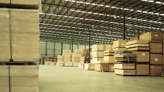 Wood processing plant in an industrial zone : Warehouse storing plywood wooden planks and furniture components neatly stacked within a well ventilated indoor facility.

