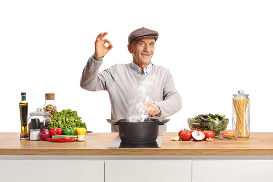 Senior man cooking a healthy homemade meal and gesturing ok sign