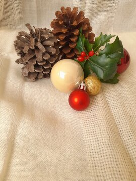 Vertical Christmas background whit pine cones and baubles on rustic fabric with copy space