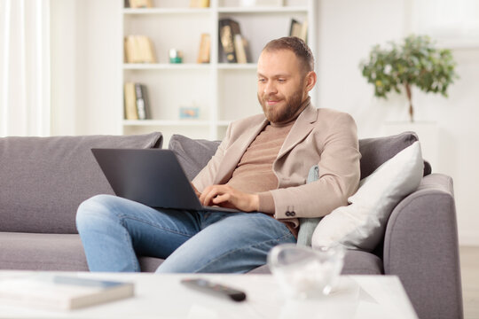Man with a laptop sitting on a sofa