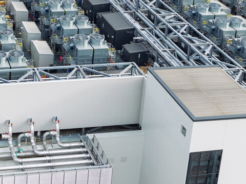 Aerial view of a data center rooftop featuring industrial cooling fans, metal piping, and technical infrastructure in the United Kingdom.