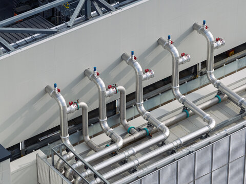 Aerial view of industrial piping and cooling system infrastructure on the exterior wall of a data center in the United Kingdom.