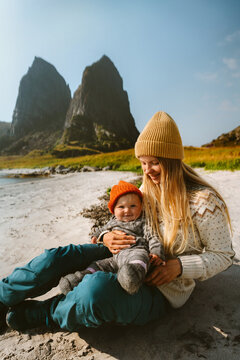 Happy mom and infant baby sitting together on beach enjoying autumn holidays family lifestyle, bonding motherhood childhood care outdoor recreation mom and kid travel in Norway candid emotions