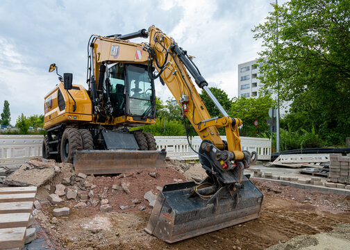 Wolfsburg, Germany - 26 Jul 2026: Yellow Caterpillar heavy wheeled excavator with bucket positioned on soil and rubble during roadwork development at construction