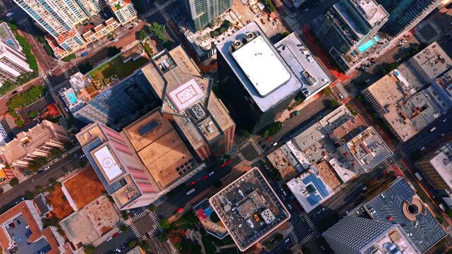 Overhead view of San Diego rooftops and intersecting streets. Buildings with rooftop helipads form a diagonal grid above crosswalks and road markings in San Diego.