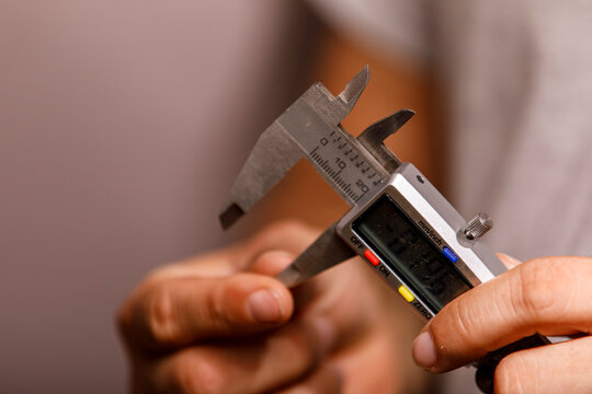 Close-up of a person's hands operating a digital caliper for accurate dimensioning.