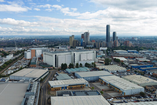 Aerial view of a large data center facility surrounded by industrial warehouses and a distant urban skyline under a cloudy sky in the United Kingdom.