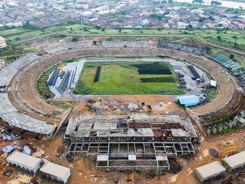 Aerial view of Ahmadu Bello Stadium under construction with heavy machinery, exposed concrete structures, and surrounding urban landscape in Kaduna, Kaduna, Nigeria.