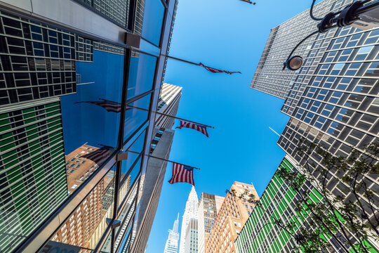 US flags and skyscrapers in Manhattan under a blue sky