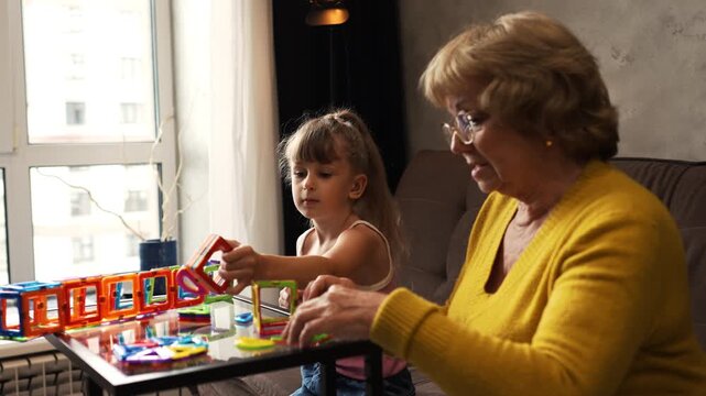 Grandmother and granddaughter building with magnetic construction toy set