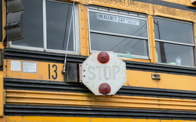 Close-up of a classic yellow school bus exterior with emergency exit windows © amip-