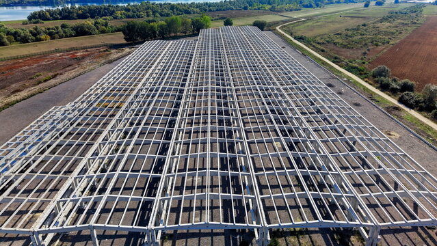 Aerial view of the large concrete hall structure under construction, featuring a vast grid of beams and columns set against a rural landscape in Kovin, Vojvodina, Serbia.