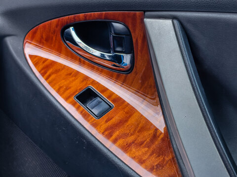 Luxury car door interior with wood grain trim and chrome handle