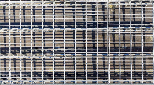 Aerial view of a metal hall structure with repeating grid patterns and long shadows cast on the ground in Kovin, Vojvodina, Serbia.