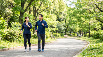 Obraz premium Happy asian couple power walking in park healthy lifestyle training fitness activity enjoying nature outdoors exercise together joy