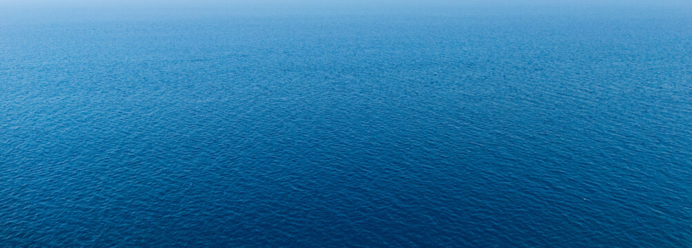 Full frame surface of a deep blue sea covered with fine wind ripples in a wide panoramic crop, natural water texture without horizon, concept of ocean background, calm and summer freshness
