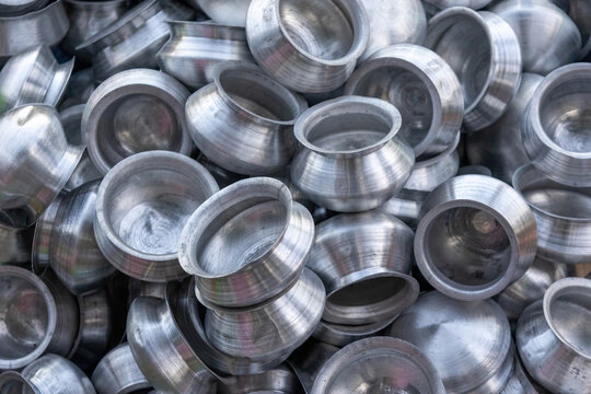 Collection of traditional aluminum cooking pots stacked together in market. Shiny metal kitchenware vessels for culinary use.