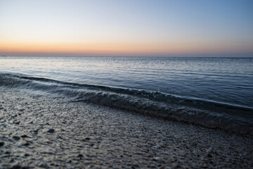 Tranquil coastal shoreline with gentle ocean waves hitting the pebble beach at twilight. © Janis Smits