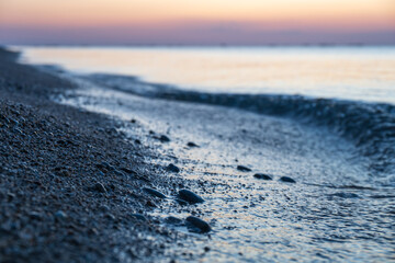 Tranquil coastal shoreline with gentle ocean waves hitting the pebble beach at twilight. © Janis Smits