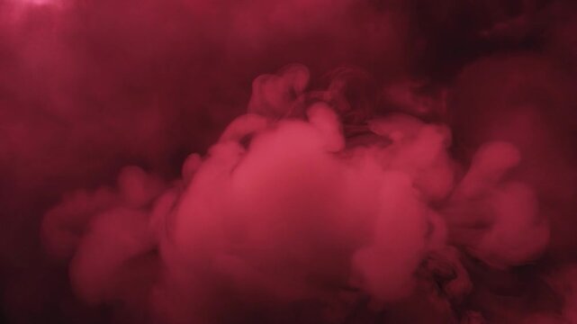 Plumes of ruby red smoke billowing upward against a dark background, creating an abstract and mysterious colorful cloud effect