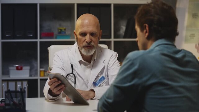 Doctor informs male patient about bad diagnosis, showing x-ray on tablet