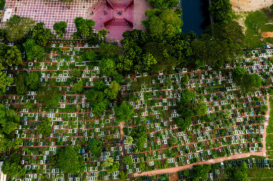 Aerial view of the dense rows of graves in Azimpur Graveyard, surrounded by lush green trees and paved walkways in Dhaka, Dhaka Division, Bangladesh.