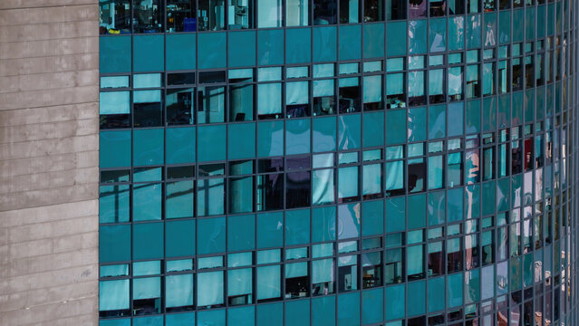 Aerial view of a modern highrise building facade with teal glass windows and concrete structural elements in Iceland.